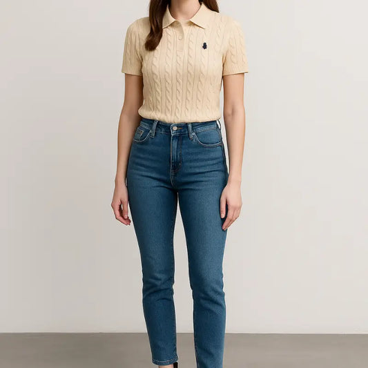 Polo femme AHMODE beige sable en maille torsadée chic, col polo et manches courtes, porté avec jean slim bleu et bottines marron.